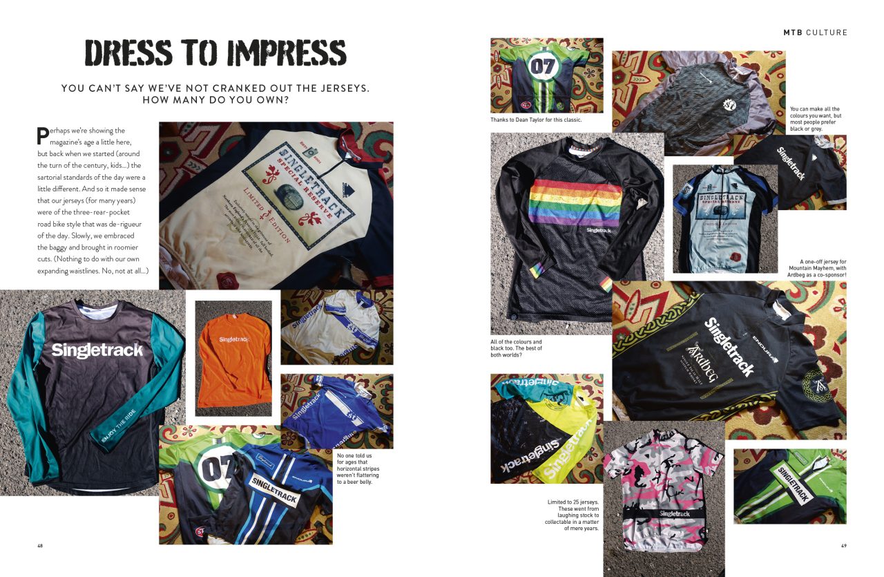 A collection of vibrant and varied mountain biking jerseys displayed on a patterned surface, including designs from Singletrack and other brands.