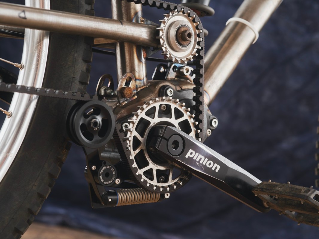 Close-up of a bicycle's pinion gearbox and belt drive system, showcasing the intricate mechanical components and adjustable linkage.