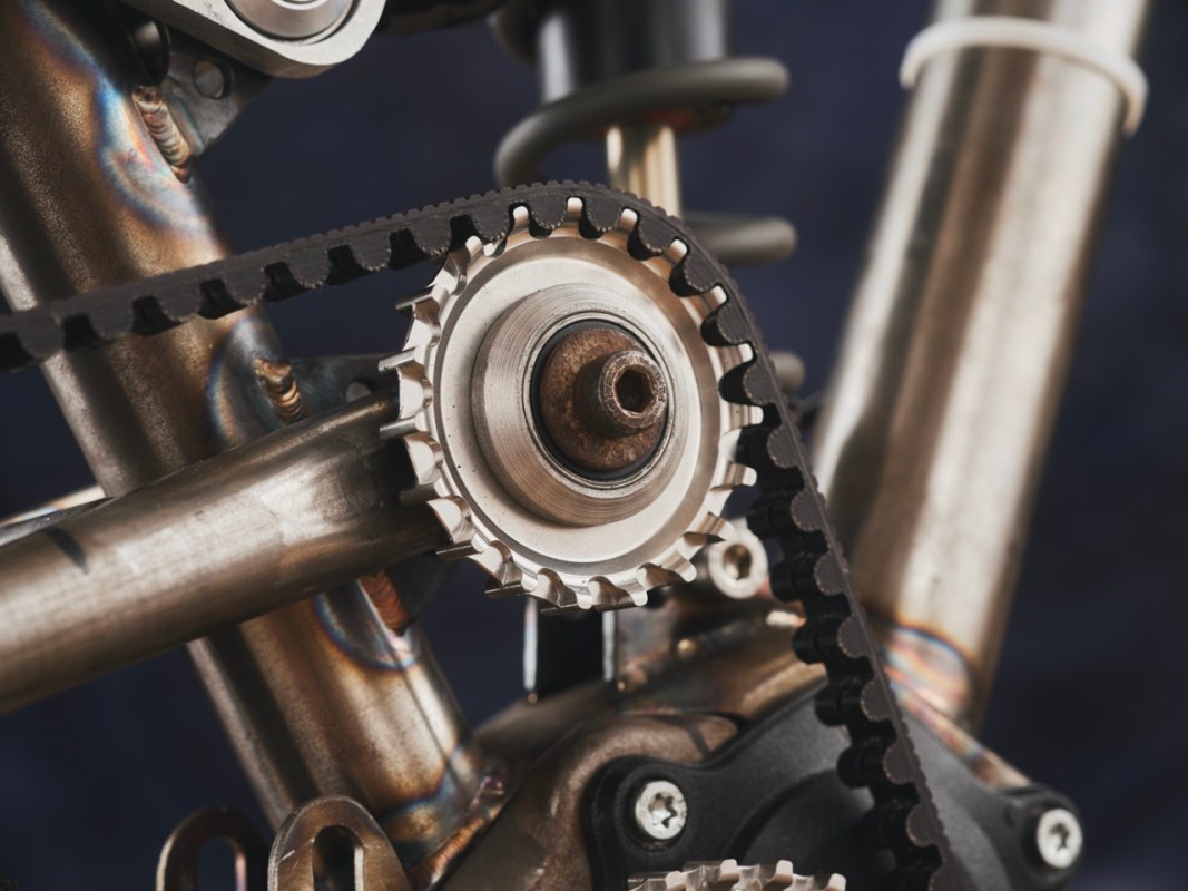 Close-up view of a bike's pinion gearbox and belt drive system, showcasing intricate metalwork and mechanical components.