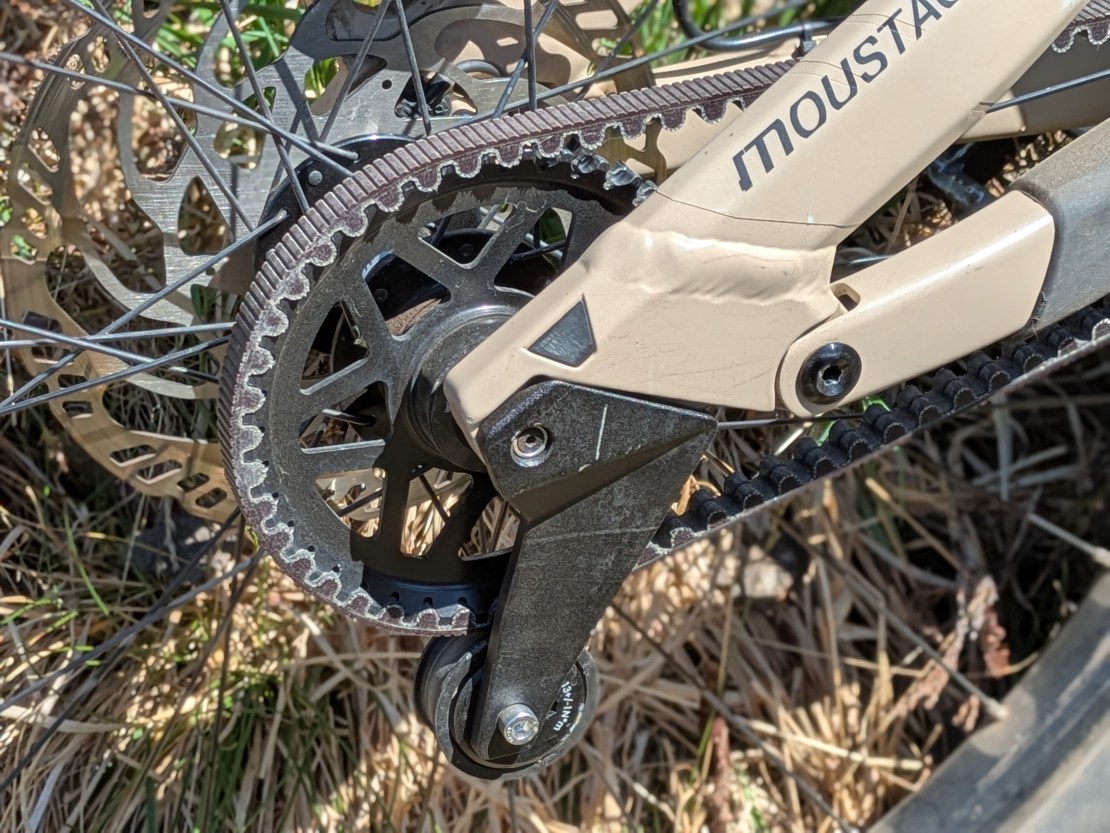 Close-up view of the Moustache Clutch's Pinion MGU gearbox motor, showcasing the belt and chainring components in a natural setting.