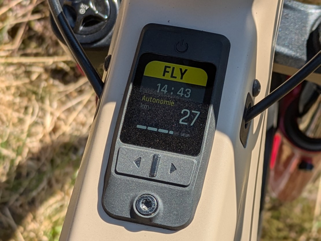 Close-up of a bicycle display showing battery level, current time, and distance traveled on a Moustache electric bike.