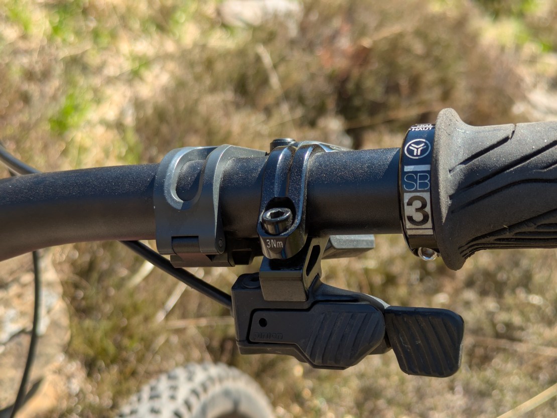 Close-up of the handlebar controls of a Moustache Clutch e-bike, featuring a gear shift mechanism and grips.