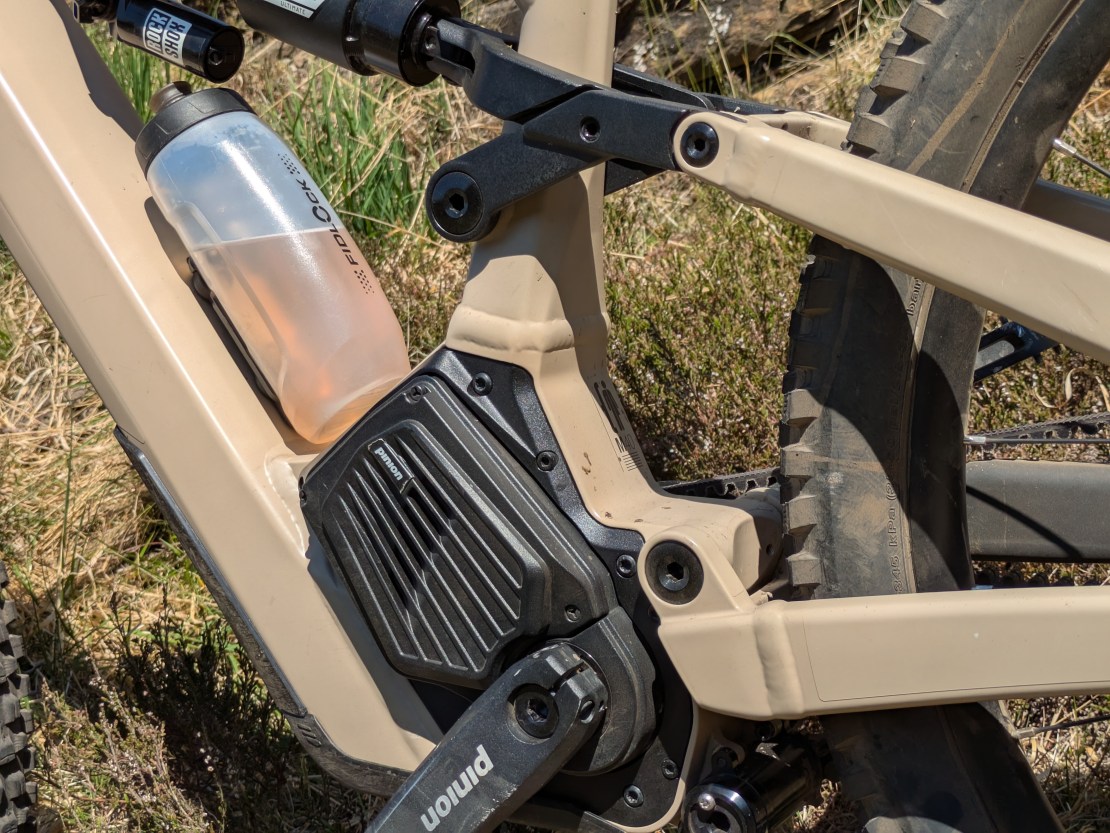 Close-up of the Moustache Clutch bike's frame showing the Pinion MGU gearbox motor and a water bottle positioned near the shock absorber.