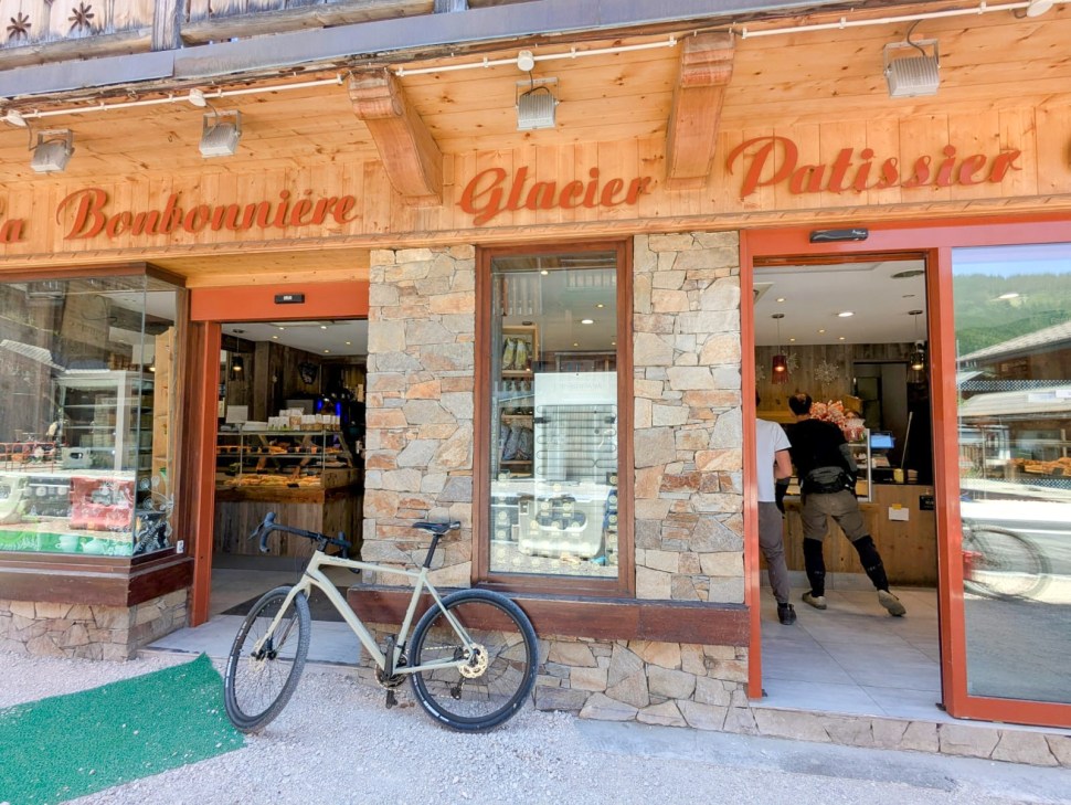 Exterior view of La Bonbonnière bakery and patisserie in Morzine, France, featuring a stone facade and a bicycle parked outside.