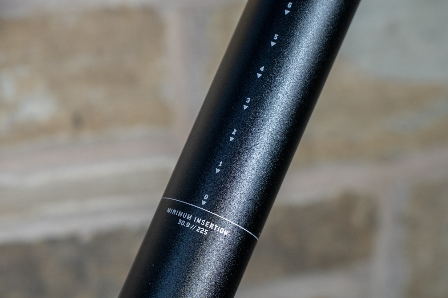 Close-up of a black bicycle seat post with measurement markings and minimum insertion information.