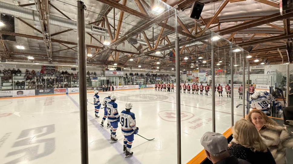 Ice hockey teams lined up on the rink with a crowd in the background at a game in Fernie, Canada.
