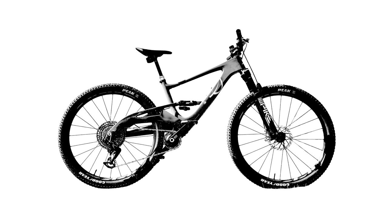 A side view of a mountain bike with a carbon frame and suspension, featuring bold tire markings and a sleek design.