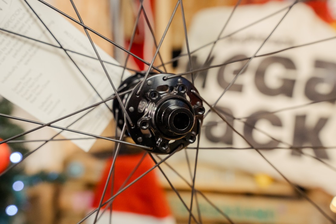 Close-up of a mountain bike wheel hub, showcasing the spokes and hub design with background featuring a 'MegaSack' banner.