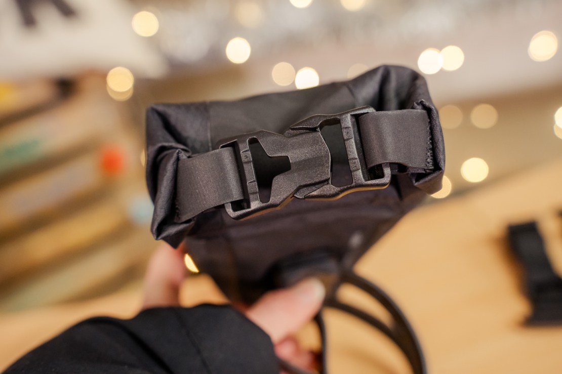Close-up view of the top of a black bag featuring a buckle closure mechanism.