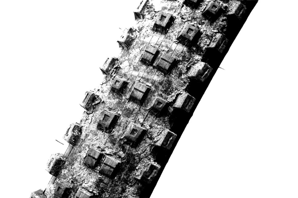 Close-up of a mountain bike tire showcasing its tread pattern and wear, presented in black and white.