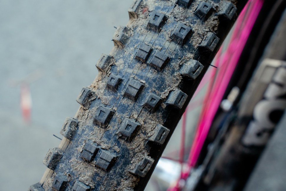 Close-up image of a Kenda Hellkat Pro mountain bike tire showing its tread pattern, slightly dirty with mud, indicating off-road use.