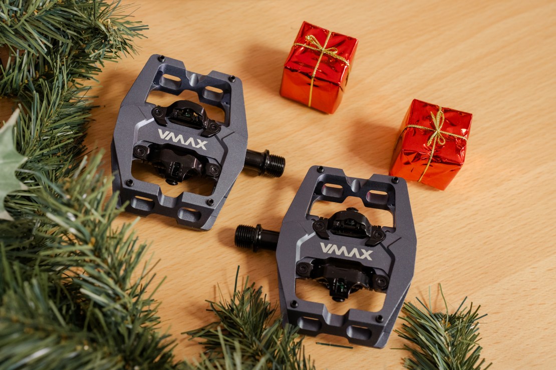 DMR VMax clip pedals arranged on a wooden surface surrounded by festive decorations, including small red gift boxes and greenery.