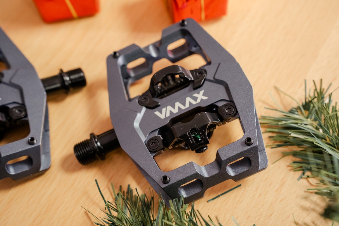 Close-up of DMR VMax clip pedals on a wooden surface, surrounded by festive greenery and gift boxes.
