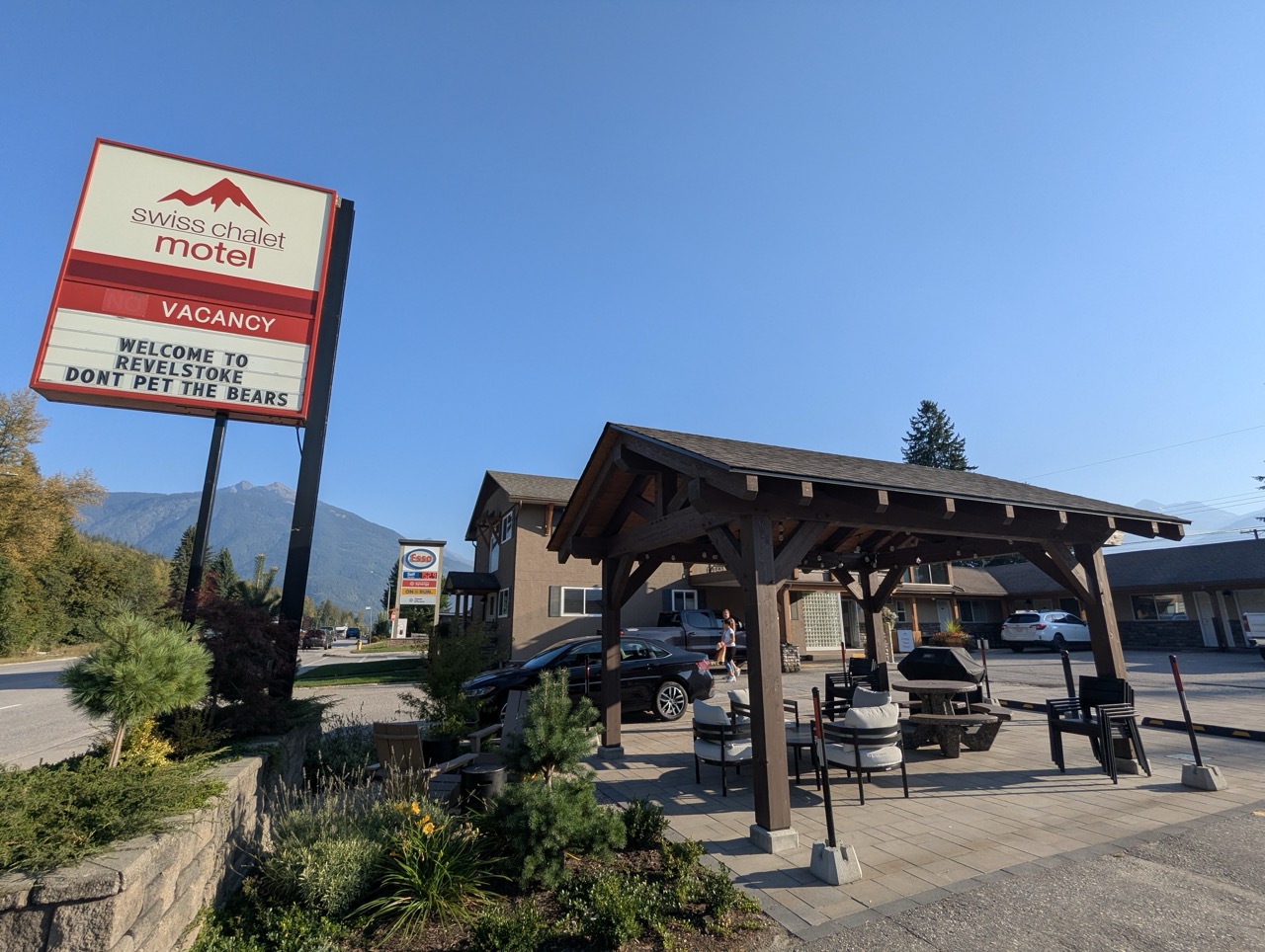 The Swiss Chalet Motel sign in Revelstoke, Canada, displaying 'Welcome to Revelstoke' and 'Don't Pet the Bears' beneath a clear blue sky.