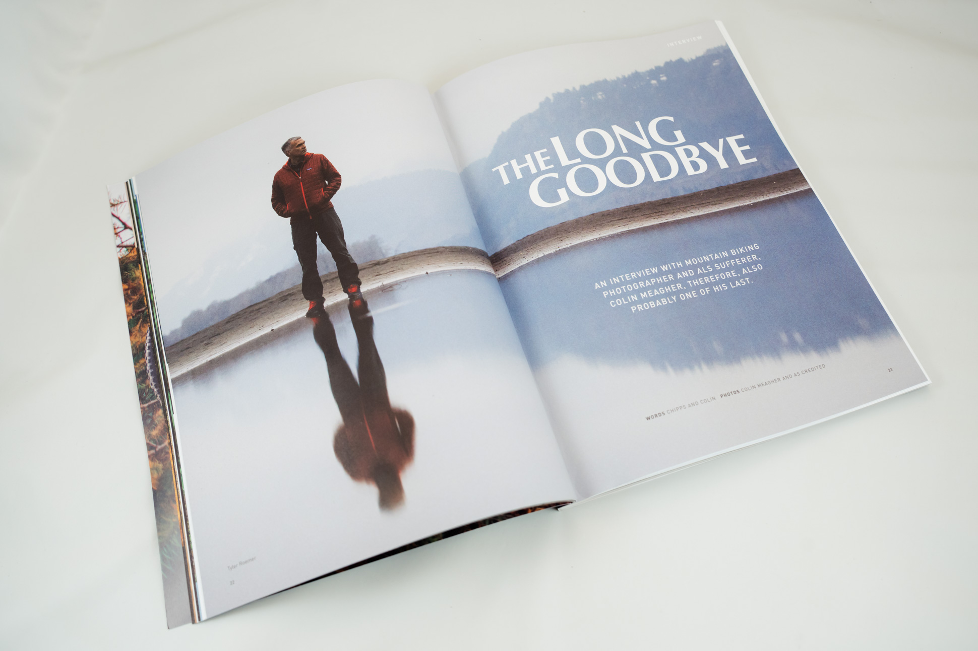 Open magazine featuring an article titled 'The Long Goodbye', showing a man in a red jacket standing by a reflective body of water.