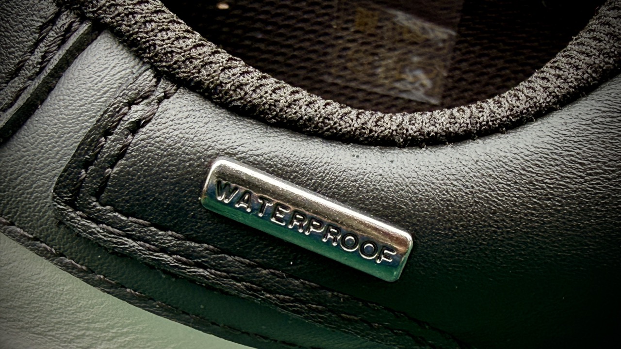 Close-up of a shoe featuring a metallic label with the word 'WATERPROOF' on a black surface. Drift ARC