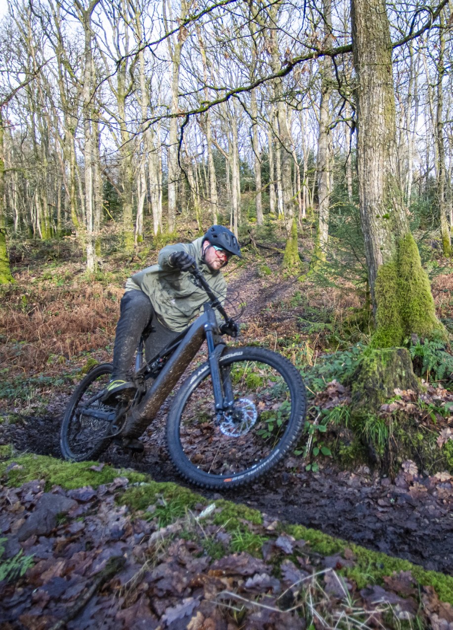 A rider riding through a muddy wooded gully.