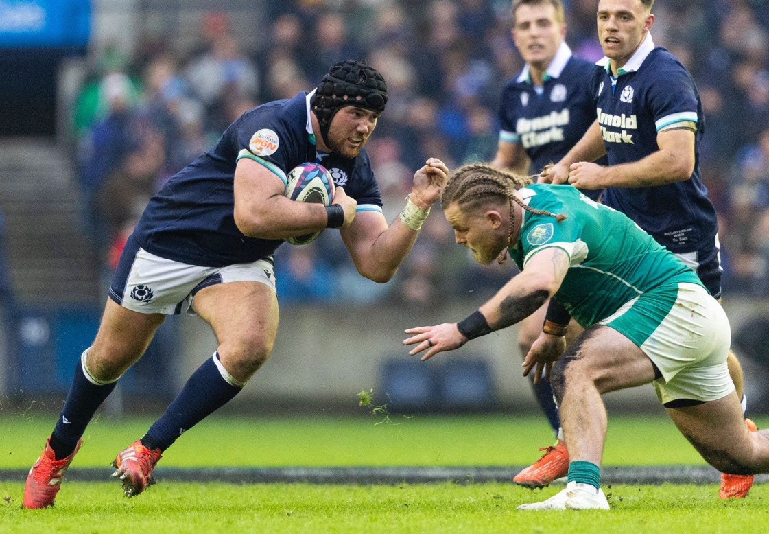 A rugby player being tackled during a Scotland versus Ireland match.