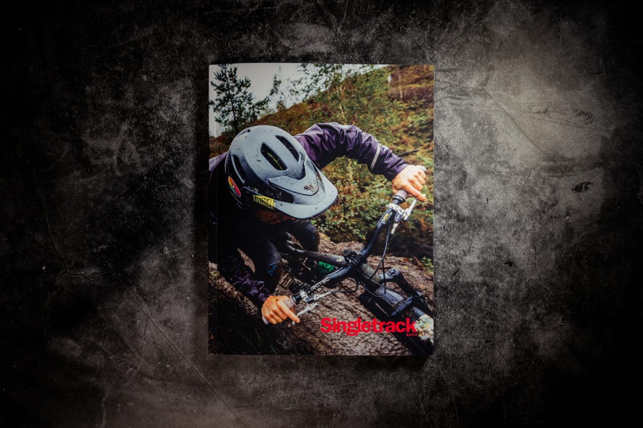 Front cover of Singletrack World Magazine Issue 167, featuring a mountain biker leaning low over the bars on a muddy, rooty trail, with the red Singletrack logo at lower right