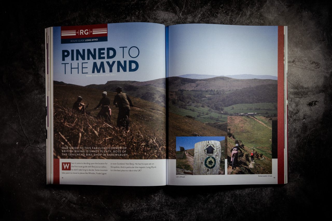 Double-page spread of 'Pinned To The Mynd', the Long Mynd route guide from Singletrack Magazine Issue 167, showing mountain bikers on grassy moorland above a patchwork valley