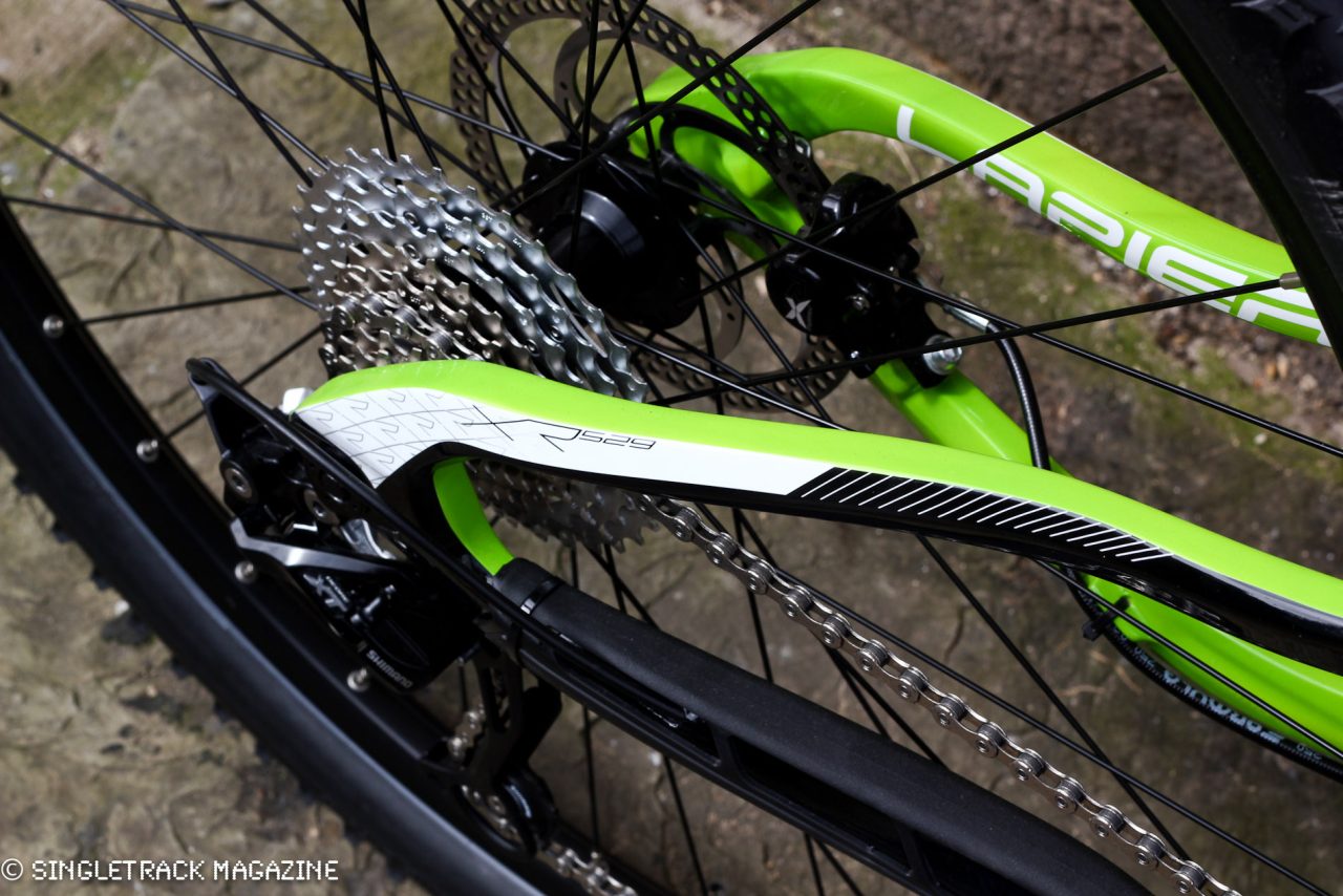 Close-up of a green and white bicycle's rear derailleur and cassette, showcasing the drivetrain components.