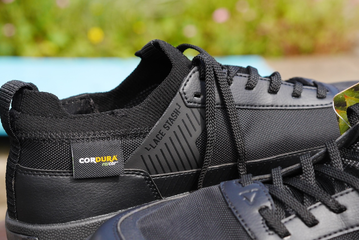 Close-up of a black shoe featuring a 'Lace Stash' design and Cordura branding, showcasing its textured materials and laces.