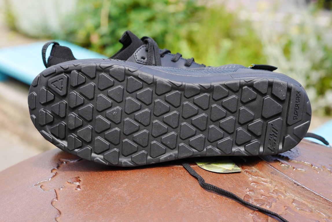 Close-up view of the sole of a black sneaker, featuring a textured pattern with triangular shapes.