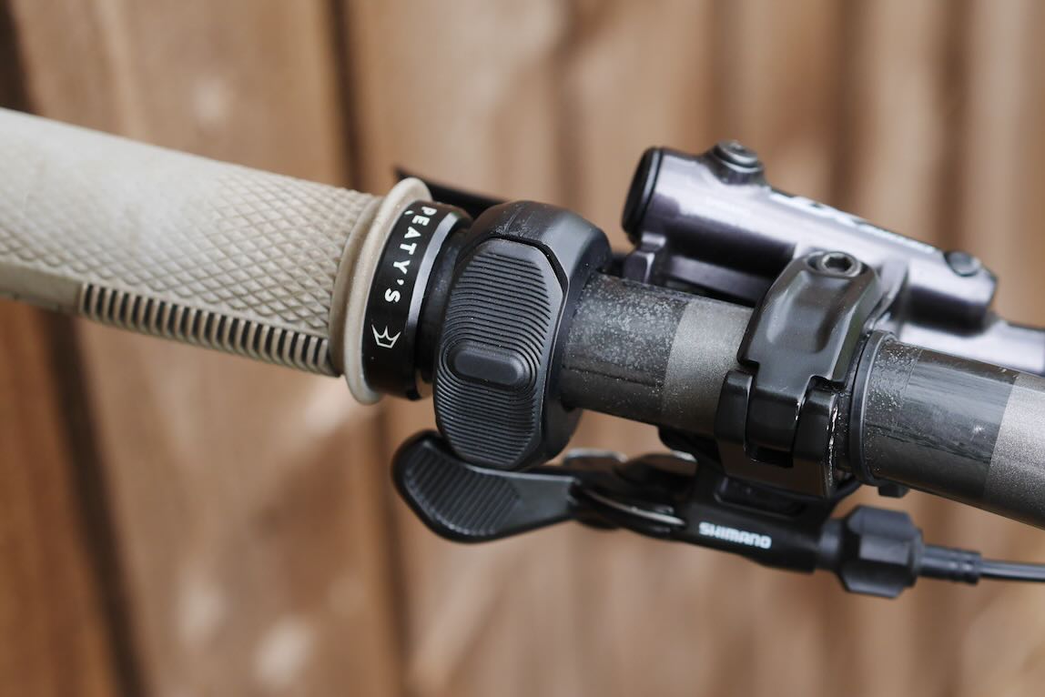 Close-up of a bicycle handlebar featuring a textured grip, a gear shifter, and a Shimano brake lever.