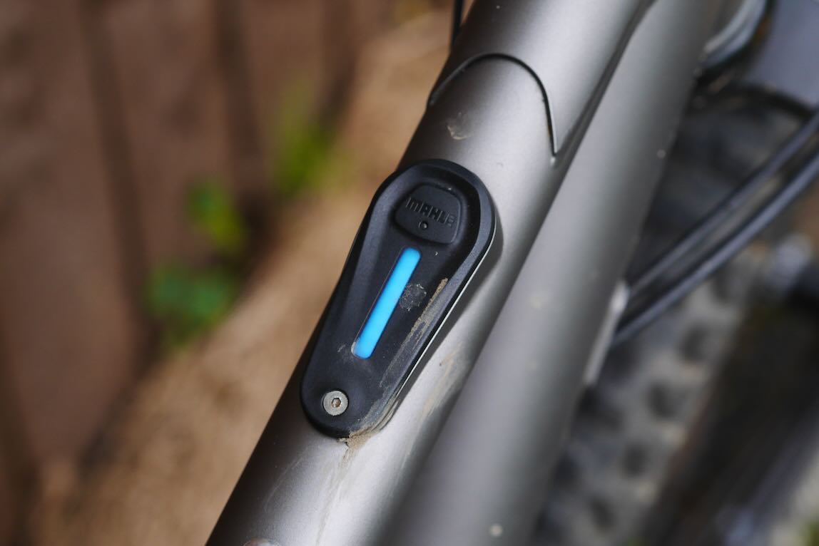 Close-up of a bike frame showing a black control button with a blue indicator light.