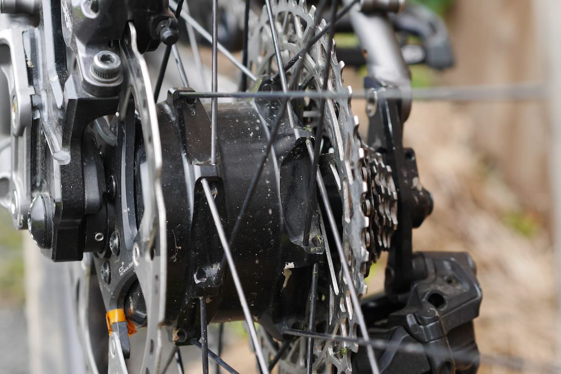Close-up of a bicycle rear wheel hub and drivetrain components, showcasing the gears and brake system.