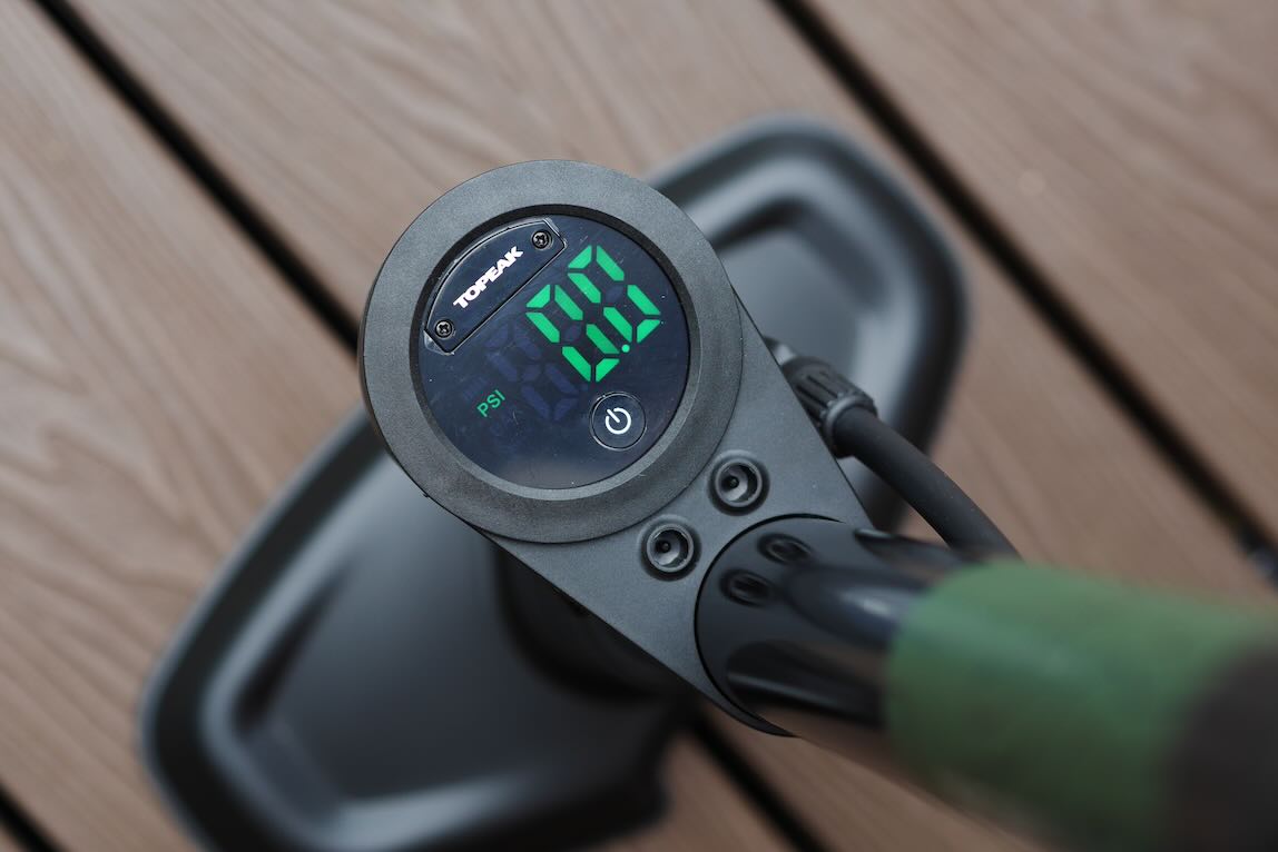 Close-up view of a digital pressure gauge showing 0 PSI, mounted on a black air pump handle.