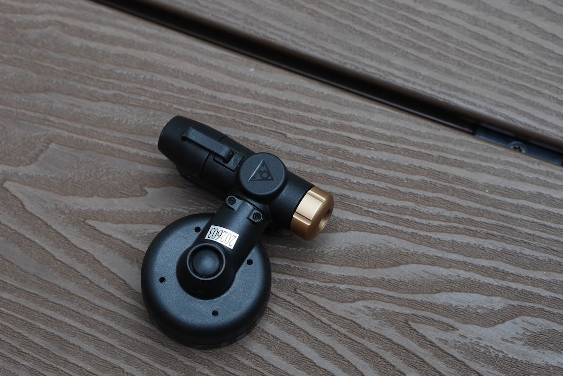 A close-up of a black and gold microphone attachment resting on a wooden surface.