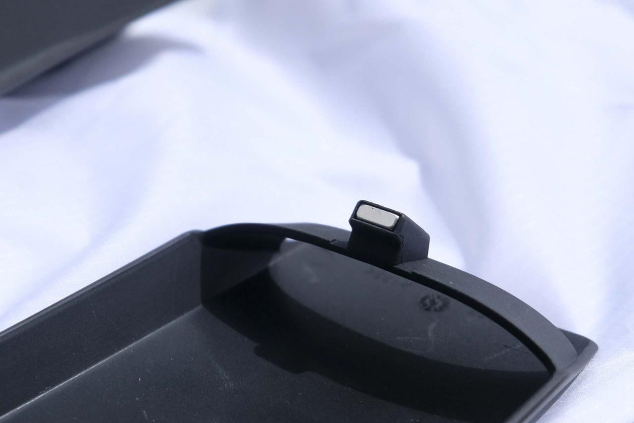Close-up of a black plastic component with a small protruding tab on a white surface.