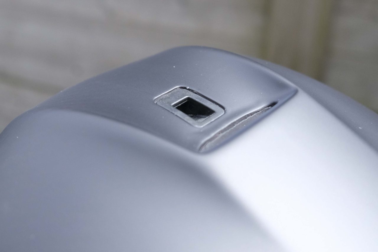 Close-up of a grey metallic surface featuring a small square opening.