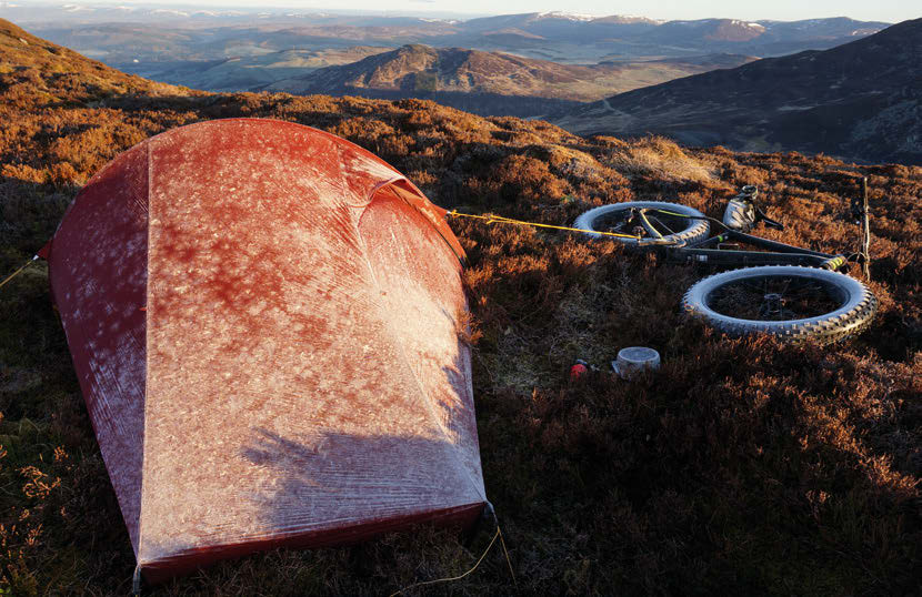 Tents and bikes coated in overnight frost at dawn on the open Highland moorland