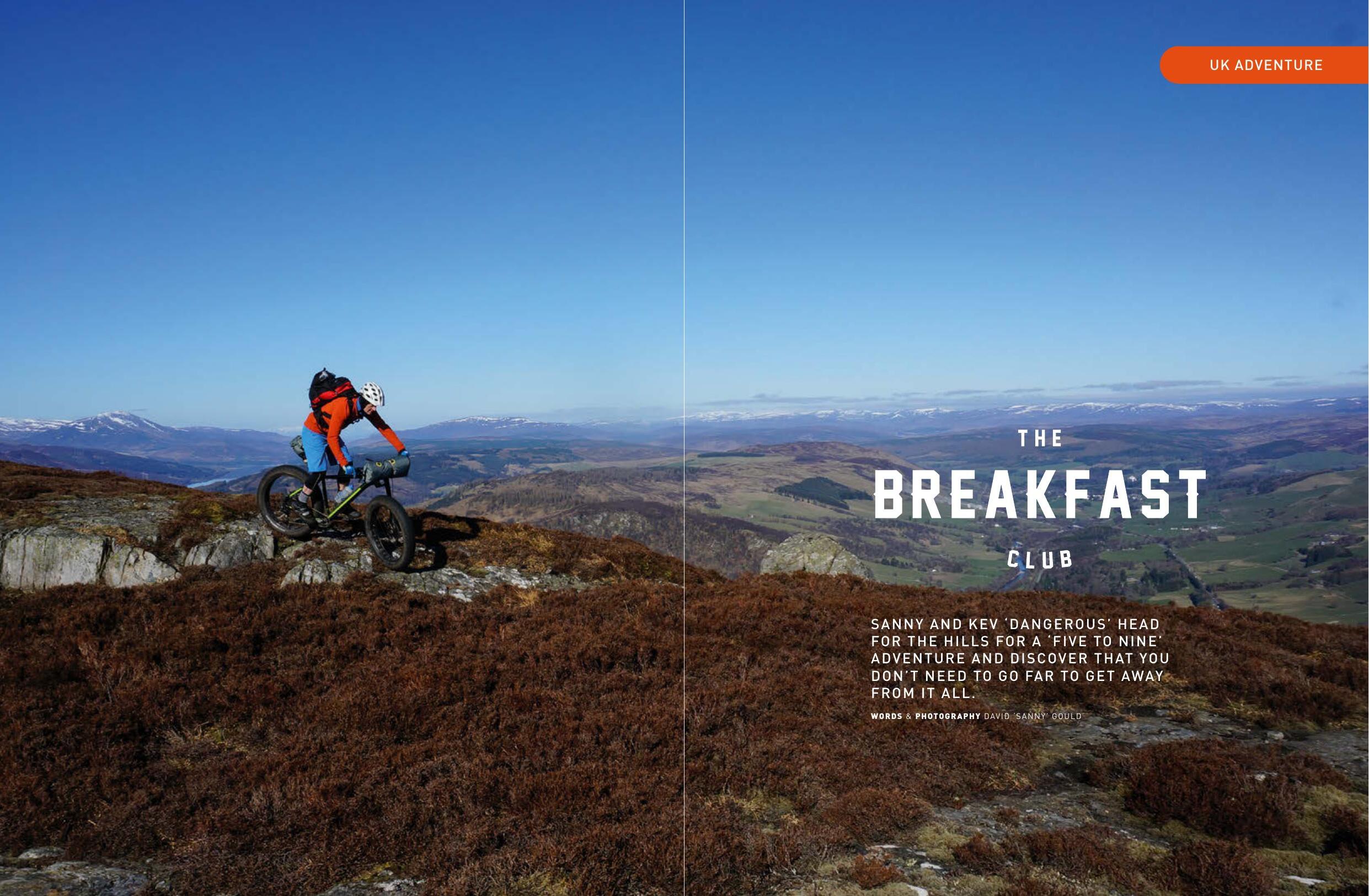 Magazine opening spread for The Breakfast Club feature, with a rider pushing a loaded fat bike up a heather-covered Highland hillside