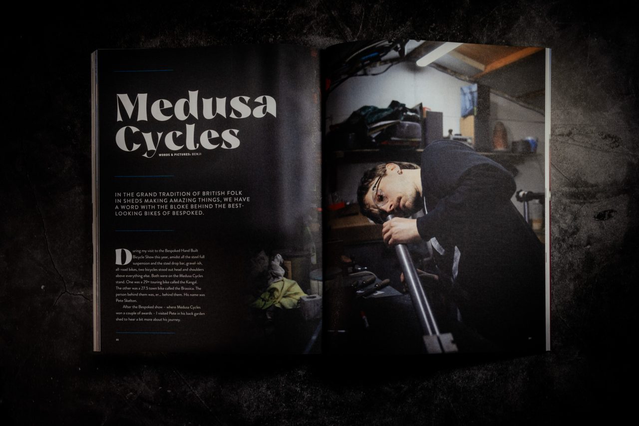 Double-page spread of 'Medusa Cycles' from Singletrack Magazine Issue 167, showing a frame builder working on a metal bike tube in a cluttered workshop