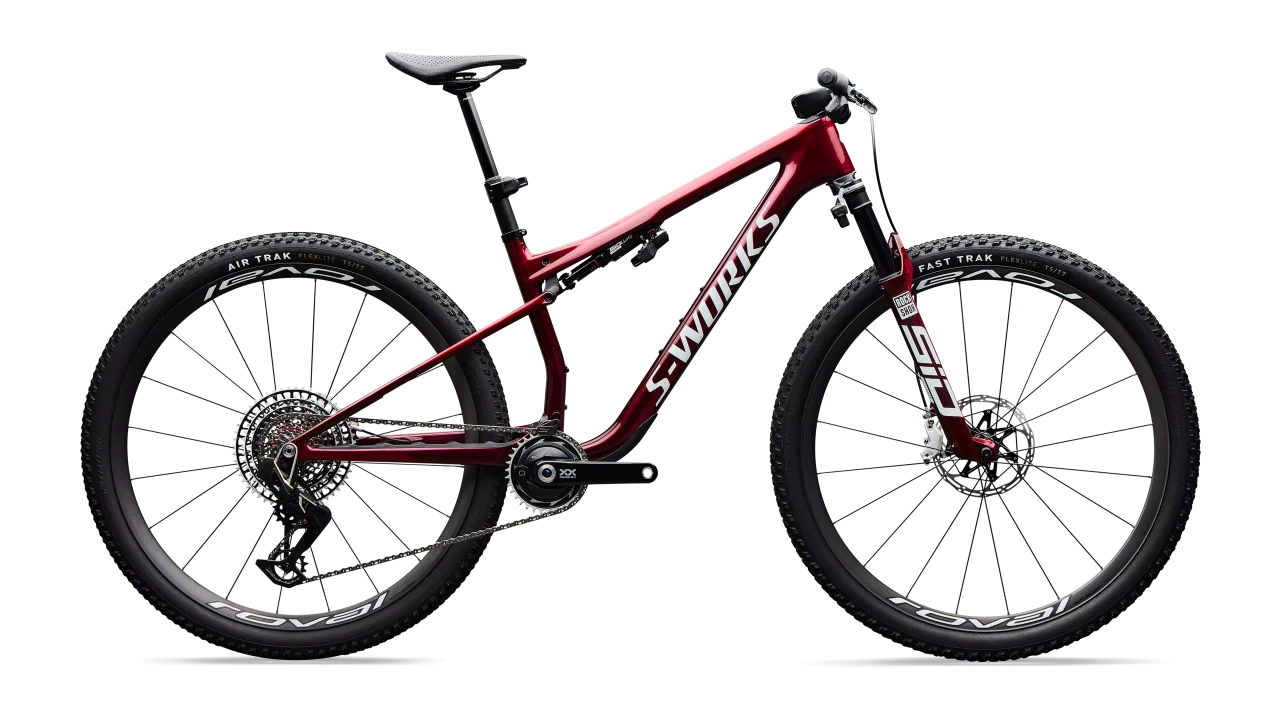 A red mountain bike featuring a sleek frame design, advanced suspension system, and high-performance tyres, showcasing its features from a side view.