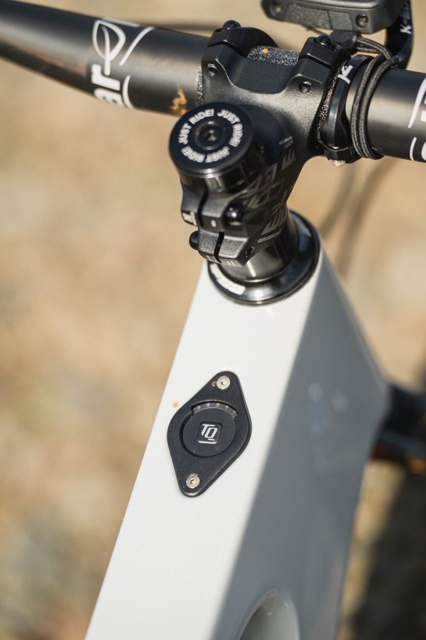 Close-up of a bicycle's stem and control buttons, featuring a black handlebar and white frame with a TD button